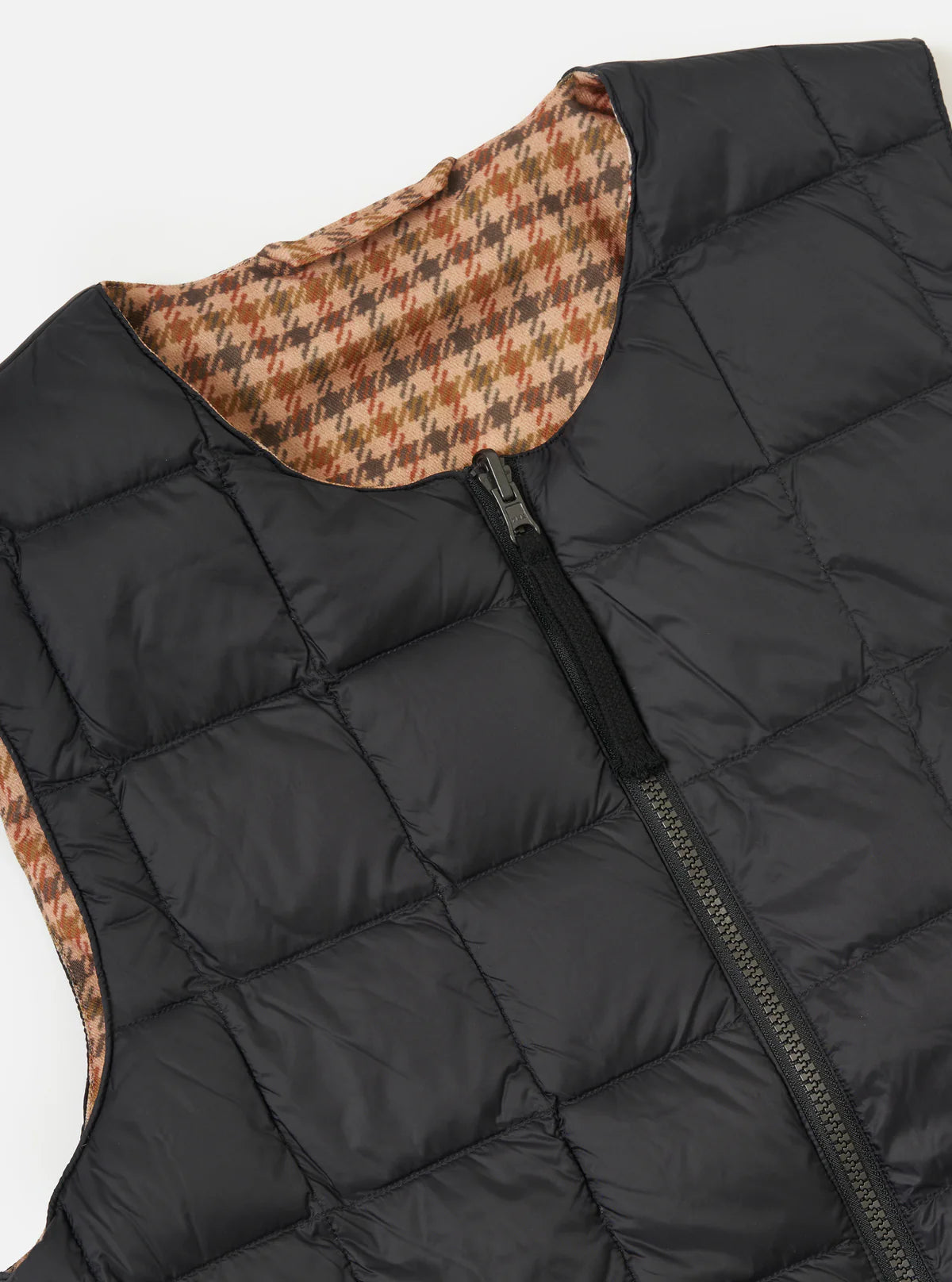 Black quilted vest with patterned inner lining on a white background