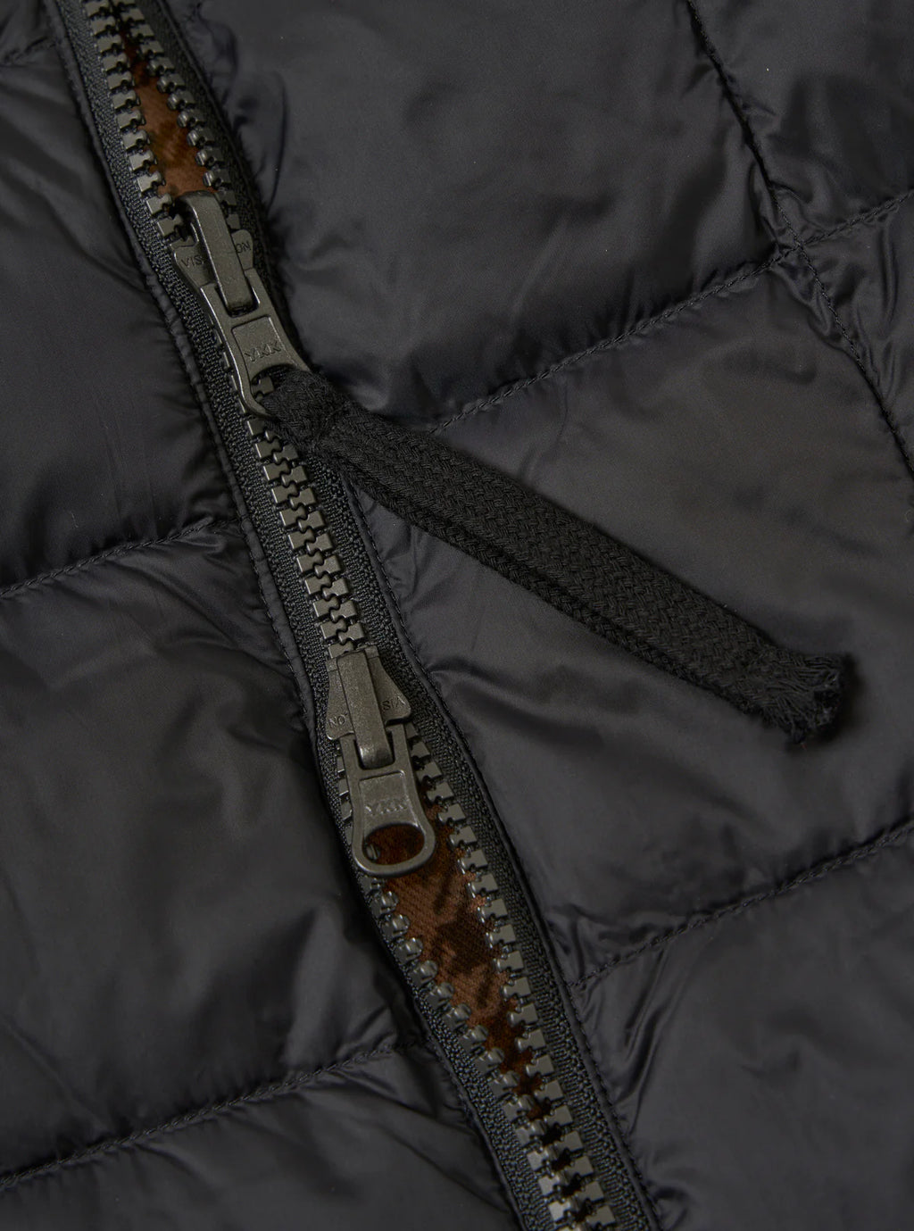 Close-up of a black puffer jacket zipper with a brown interior lining.