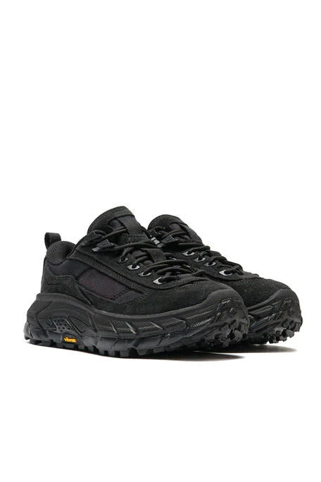 A pair of black rugged outdoor sneakers with chunky laces and thick, textured black soles, shown against a plain white background.